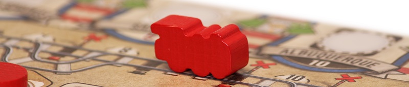 closeup of a red game board piece in the shape of a train, placed upon the game board